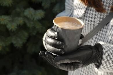 Photo of Woman with coffee in paper cup outdoors, closeup. Space for text