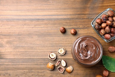 Photo of Flat lay composition with tasty chocolate hazelnut spread on wooden table, space for text