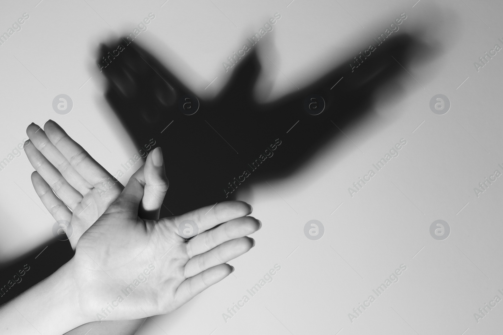 Photo of Woman making hand gesture like bird on light background, closeup with space for text. Black and white effect