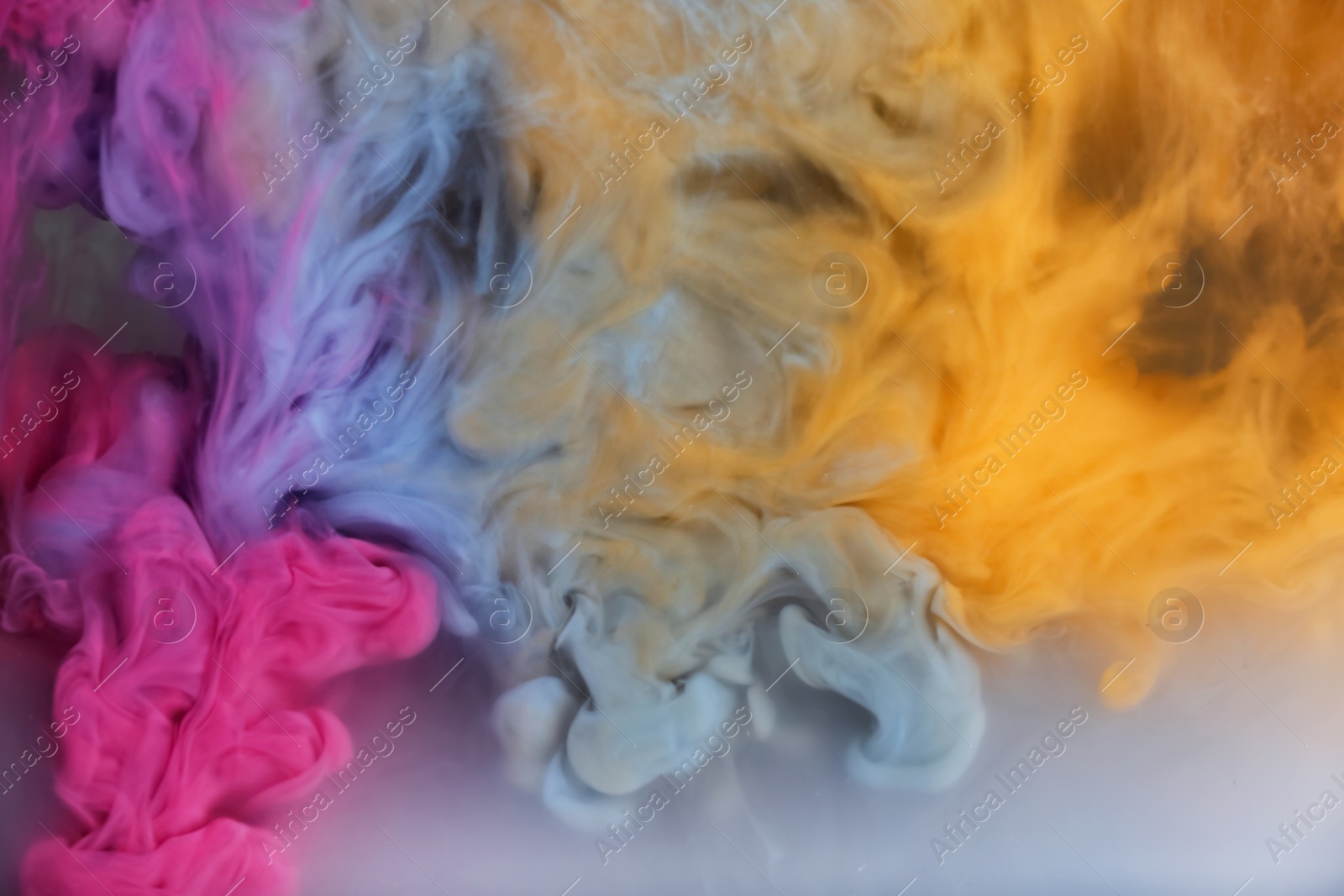 Photo of Splash of pink, light blue and yellow inks on grey background