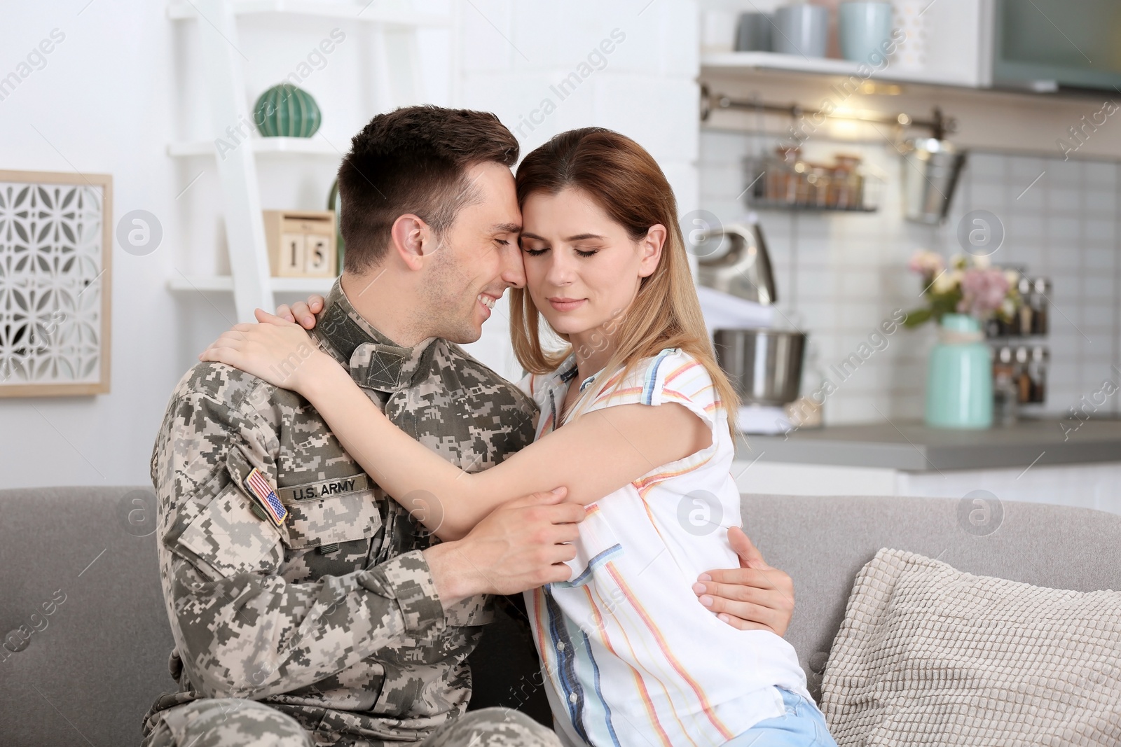 Photo of Young man in military uniform with his wife on sofa at home