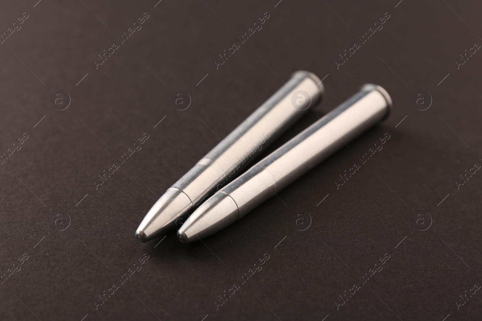 Photo of Two metal bullets on black background, closeup