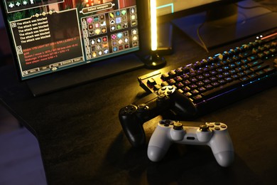 Playing video games. Computer monitor, keyboard and wireless controllers on table indoors