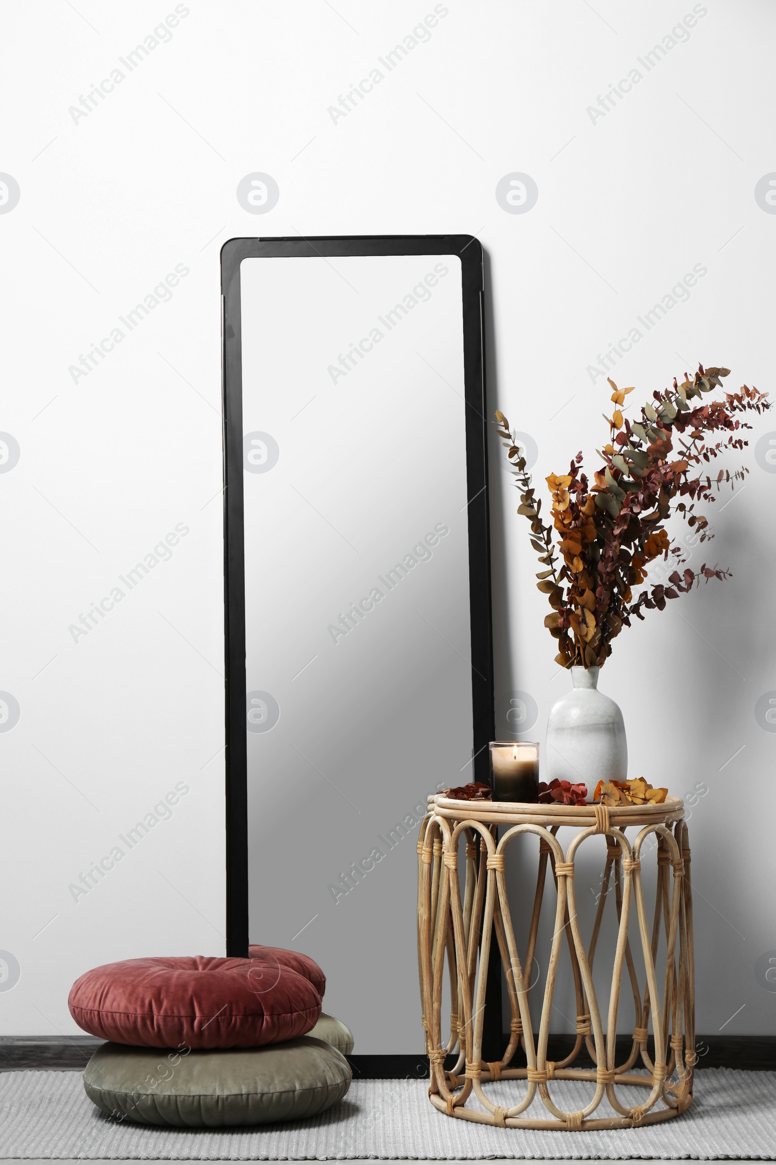 Photo of Table, mirror and pillows on floor near white wall