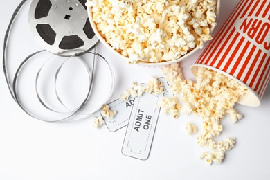 Popcorn, tickets and movie reel on white background, top view. Cinema snack