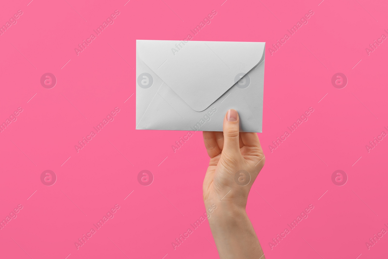 Photo of Woman holding white paper envelope on pink background, closeup