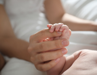 Photo of Mother with her newborn baby, closeup on hands