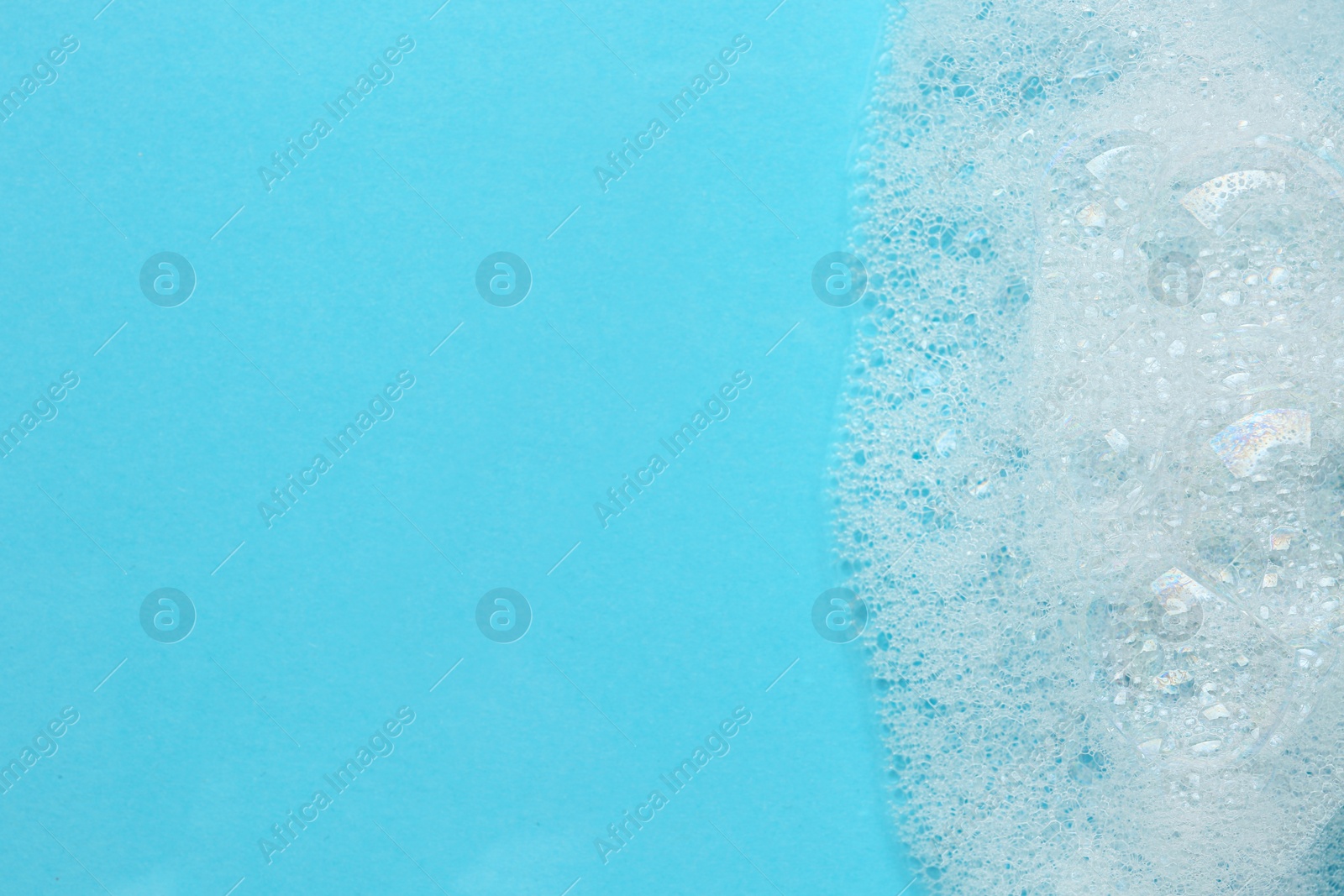 Photo of Fluffy bath foam on turquoise background, top view. Space for text