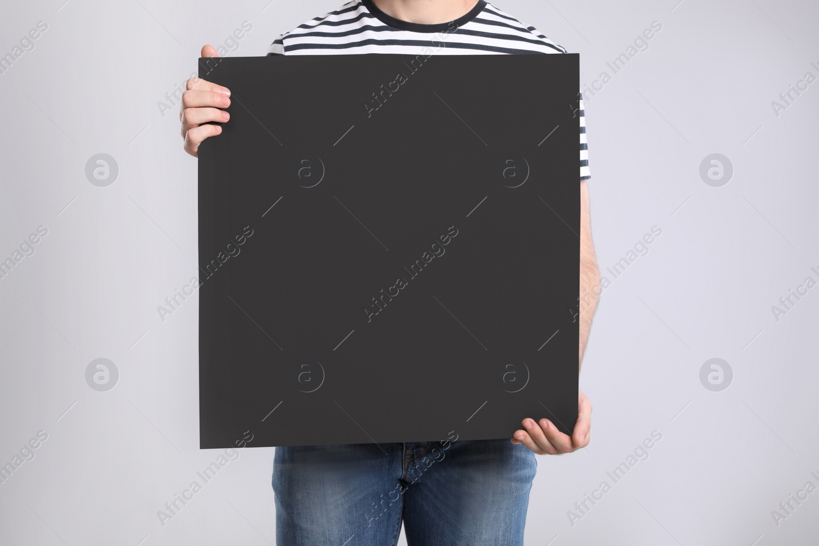 Photo of Man holding blank poster on light grey background, closeup