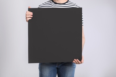 Photo of Man holding blank poster on light grey background, closeup