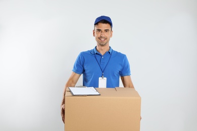 Photo of Happy young courier with cardboard box and clipboard on white background