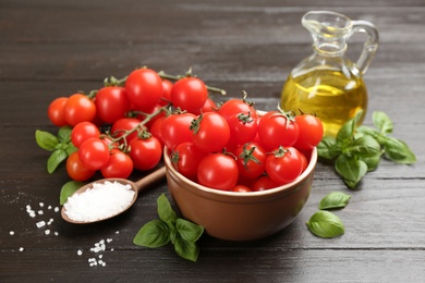 Photo of Fresh cherry tomatoes, basil and sea salt on wooden table