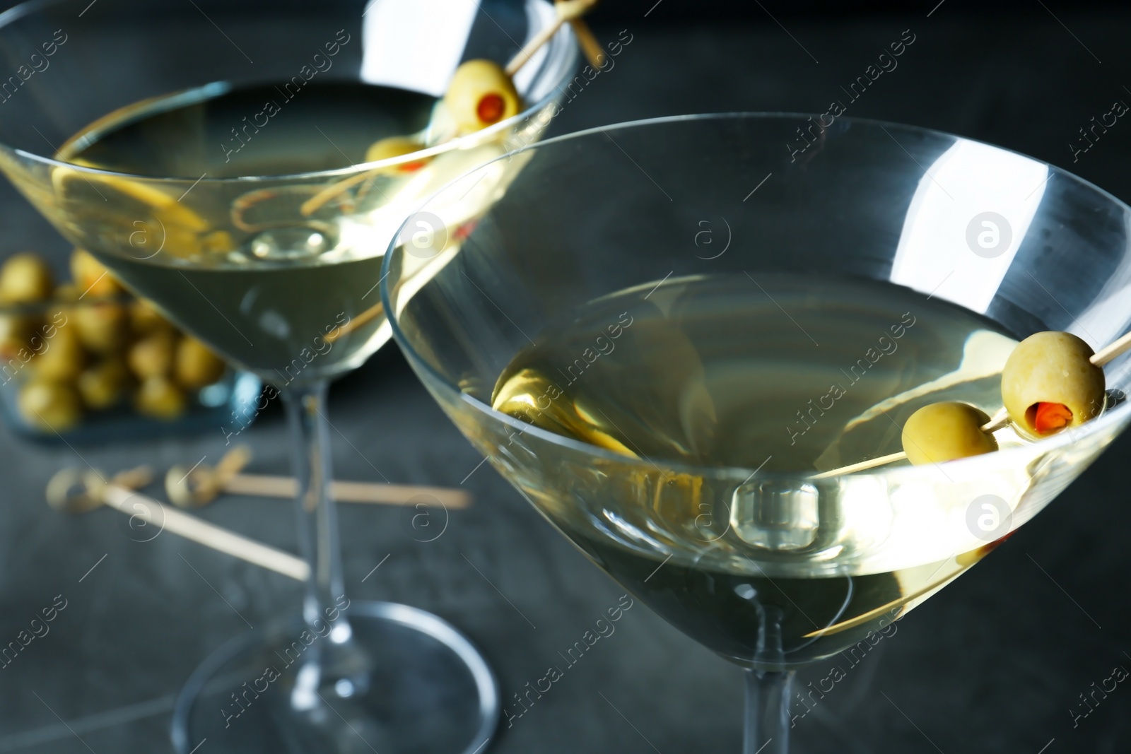 Photo of Glasses of Classic Dry Martini with olives on dark table, closeup