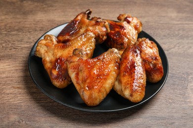 Plate with delicious fried chicken wings on wooden table