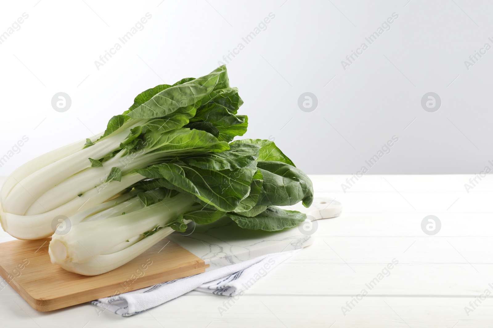 Photo of Fresh green pak choy cabbages on white wooden table, space for text