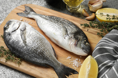 Photo of Raw dorada fish and ingredients on grey table