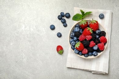 Photo of Mix of different fresh berries in bowl on light grey table, flat lay. Space for text