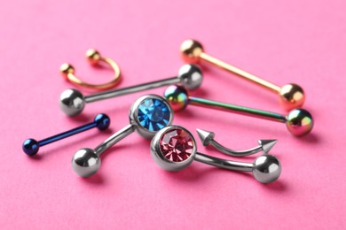 Stylish jewelry for piercing on pink background, closeup