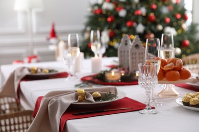 Photo of Christmas table setting with beautiful napkin, cutlery and dishware indoors