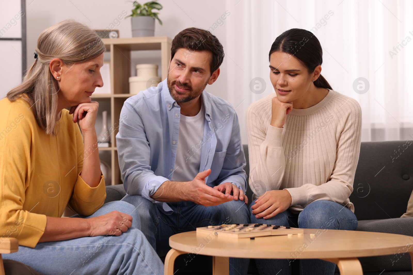 Photo of Family talking while playing checkers at home