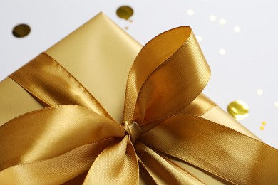 Photo of Beautiful golden gift box with bow, closeup