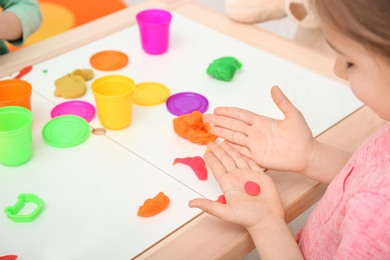 Photo of Cute little girl using play dough at table, closeup