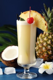 Tasty Pina Colada cocktail and ingredients on blue wooden table