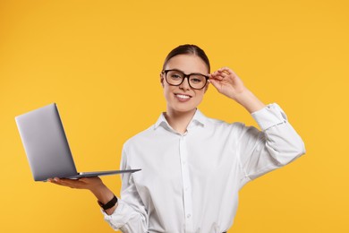 Photo of Happy woman in glasses with laptop on orange background