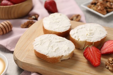 Delicious bruschettas with ricotta cheese, strawberries and walnuts on table, closeup