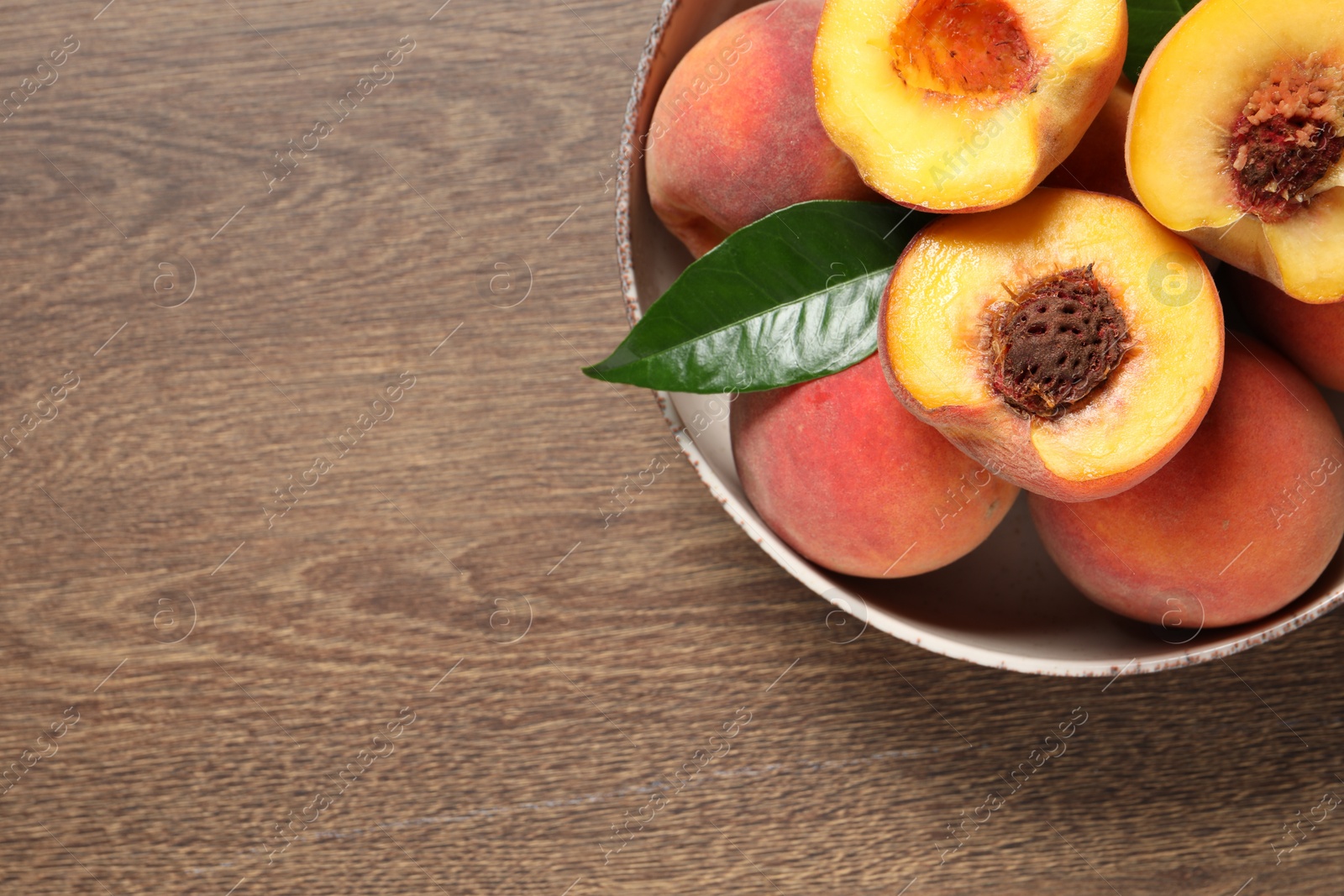 Photo of Plate with delicious juicy peaches and leaf on wooden table, top view. Space for text