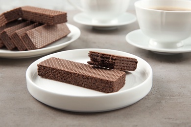 Photo of Delicious chocolate wafers with cup of coffee on grey stone background