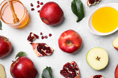 Photo of Honey, apples and pomegranates on light table, flat lay. Rosh Hashanah holiday