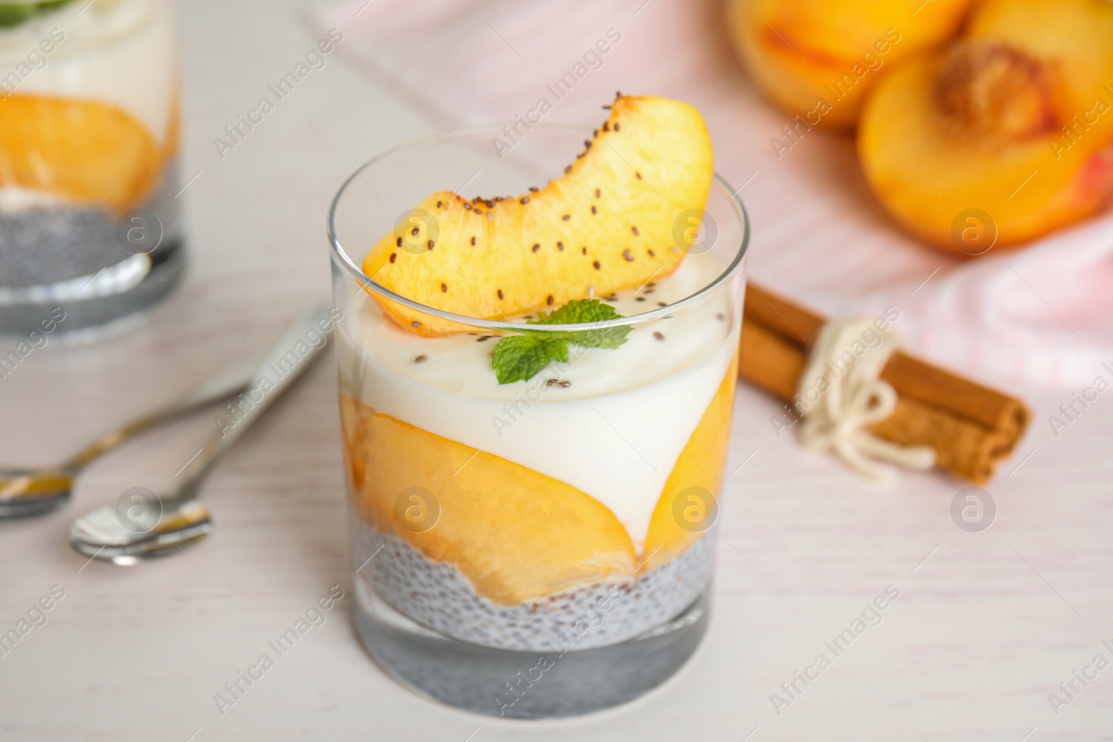 Photo of Tasty peach dessert with yogurt and chia seeds on white wooden table