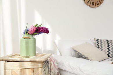 Photo of Beautiful hyacinths in metal can on wooden crate indoors, space for text. Spring flowers