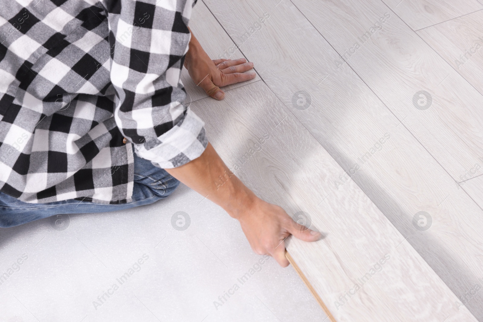 Photo of Professional worker installing new laminate flooring, closeup