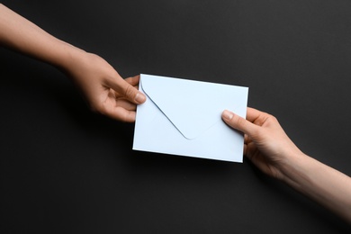 Photo of Women holding envelope on black background, top view
