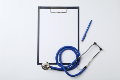 Photo of Clipboard with space for text, pen and stethoscope on white background, top view. Medical objects