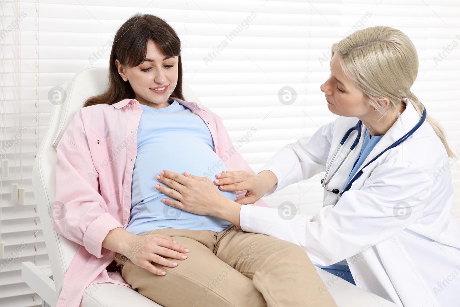 Photo of Pregnancy checkup. Doctor examining patient's tummy in clinic