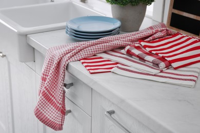 Different towels and stack of plates near sink on kitchen counter