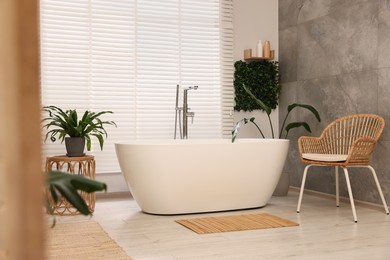 Green artificial plants and tub near window in bathroom