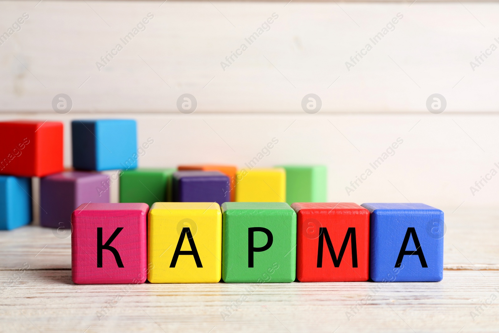 Photo of Word Karma made of colorful cubes with letters on white wooden table