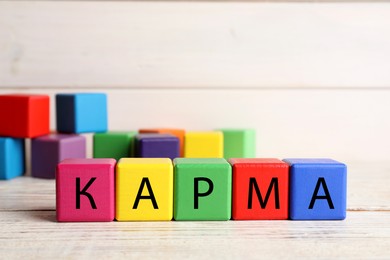 Word Karma made of colorful cubes with letters on white wooden table