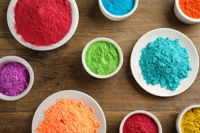Photo of Colorful powder dyes on wooden background, flat lay. Holi festival