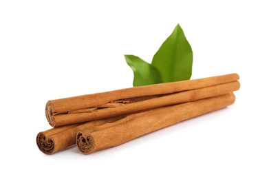 Photo of Aromatic dry cinnamon sticks and green leaves on white background