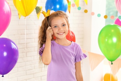 Photo of Happy girl near bright balloons at birthday party indoors