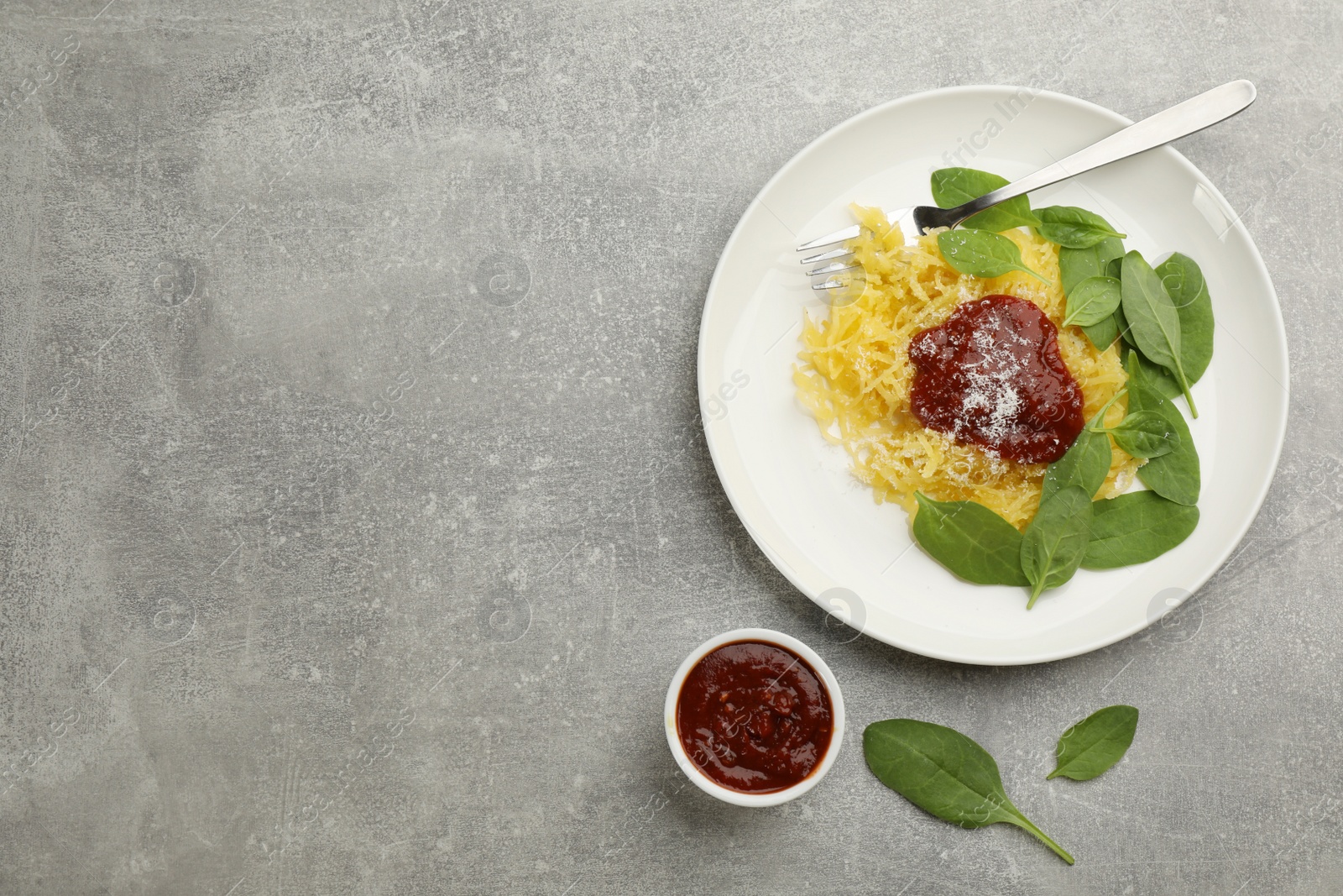 Photo of Tasty spaghetti squash with tomato sauce, cheese  and basil served on light grey table, flat lay. Space for text