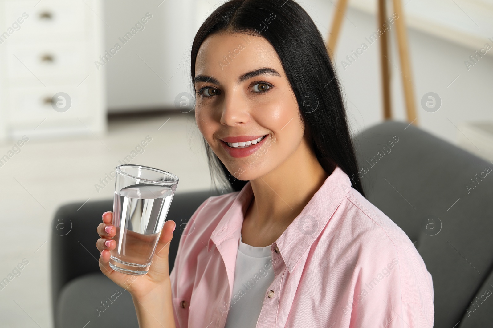 Photo of Young woman with glass of water indoors. Refreshing drink