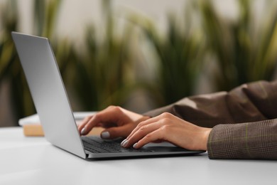 Photo of Woman using modern laptop at desk in office, closeup