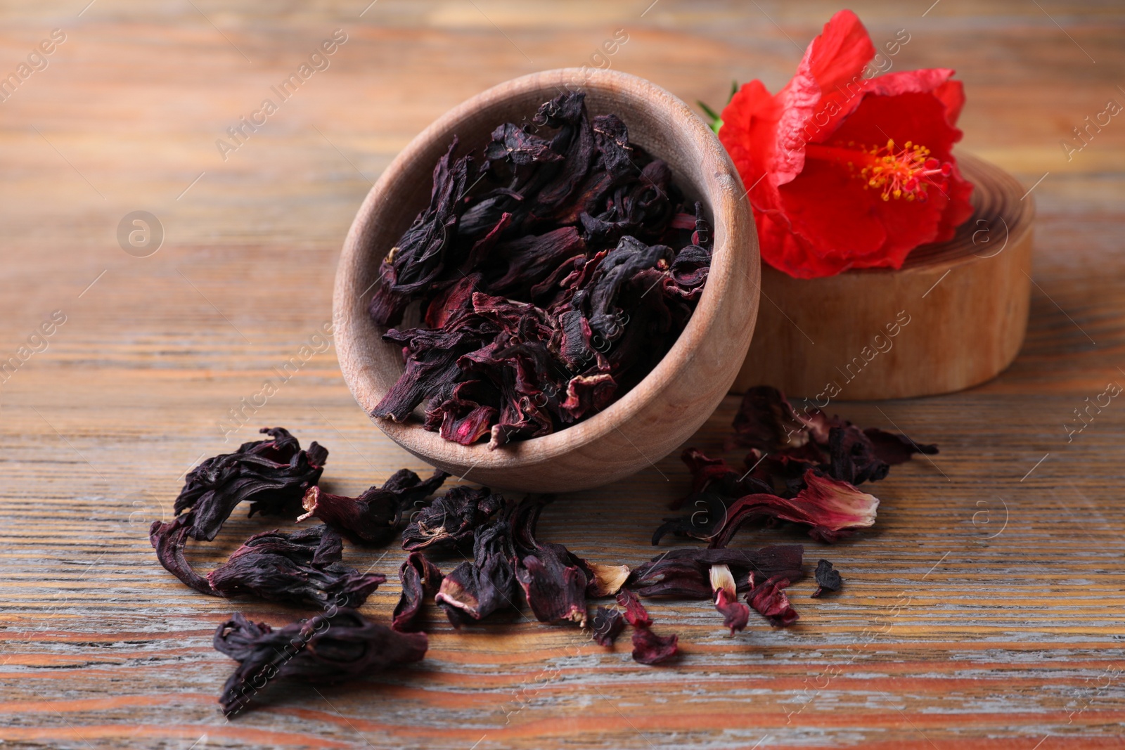 Photo of Dry hibiscus tea and flower on wooden table