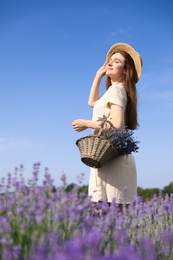 Photo of Young woman with wicker basket full of lavender flowers in field